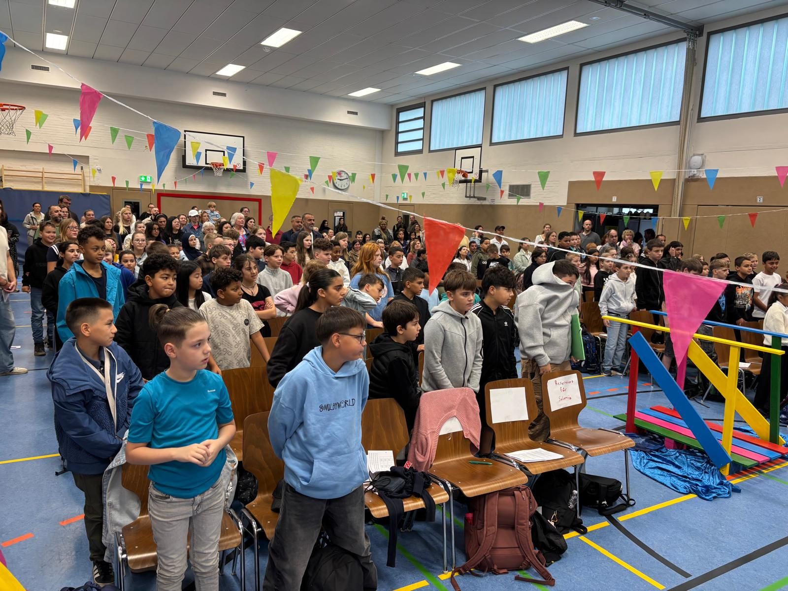 Die mit bunten Wimpeln geschmückte Sporthalle, voll mit den neuen Fünftklässlern und ihren Familien.