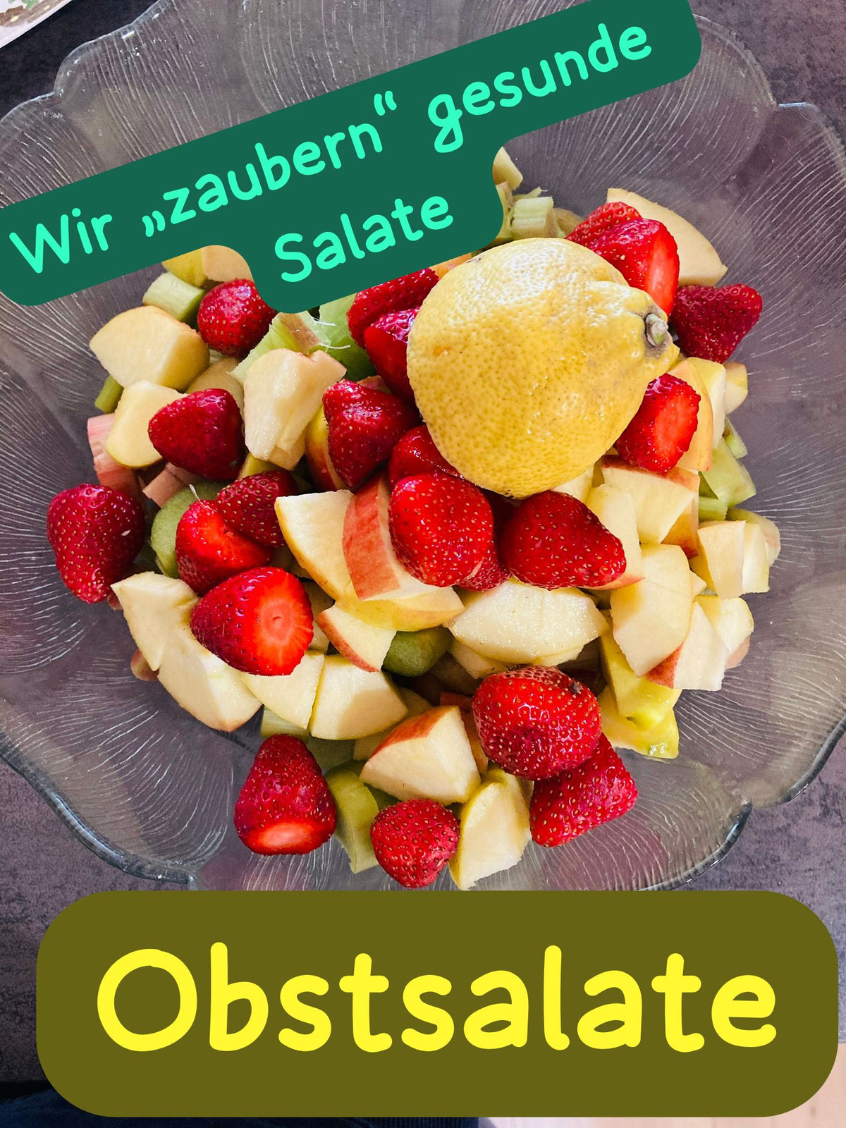 Glasschüssel mit Obstsalat aus Erdbeeren, Äpfeln und einer Zitrone