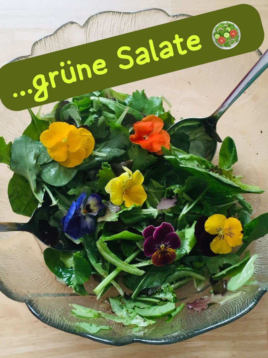 Glasschüssel mit grünem Salat und bunten essbaren Blüten