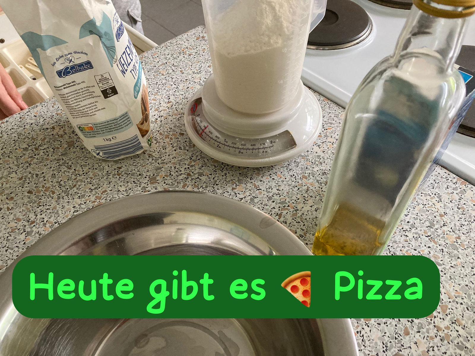 Mehl, Messbecher auf der Küchenwaage, Öl und eine Schüssel auf der Arbeitsfläche